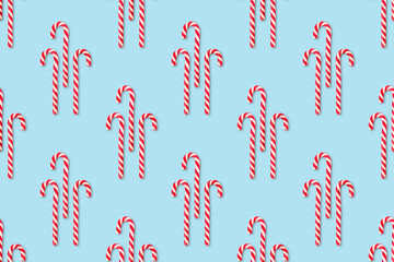 Christmas seamless pattern made of striped candy cane on a blue pastel background. Background made of food. Christmas and New year concept. Top view. Flat lay. Minimal composition