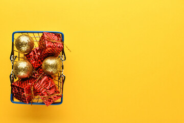 Christmas gifts and toys in a basket on a bright yellow background, empty space for text on the right. New year and Christmas background.