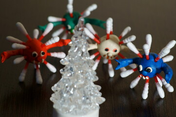 Figures of multi-colored viruses on the table. There is a small Christmas tree nearby.