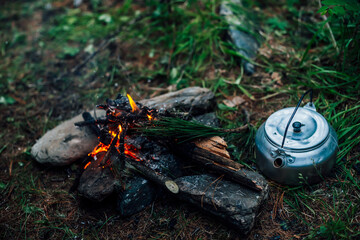 Camping kettle near small camp fire close-up. Cozy camping place in wild. Wonderful evening atmospheric background of campfire. Beautiful flame of small magic bonfire. Romantic warm place with fire.
