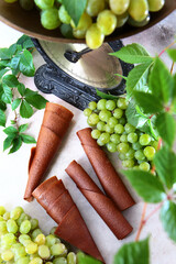 Light grapes and vintage scales. Pastilla from grapes. Natural product without preservatives. Food for vegetarians. Bunches of grapes on a light background. Vertical photo.