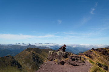 Stone landmark at the top of Ayous peak with views of the peaks and mountains of the Pyrenees with some cloud