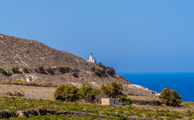 Fototapeta na wymiar A view along the coast towards the lighthouse at Akortiri in Santorini in summertime