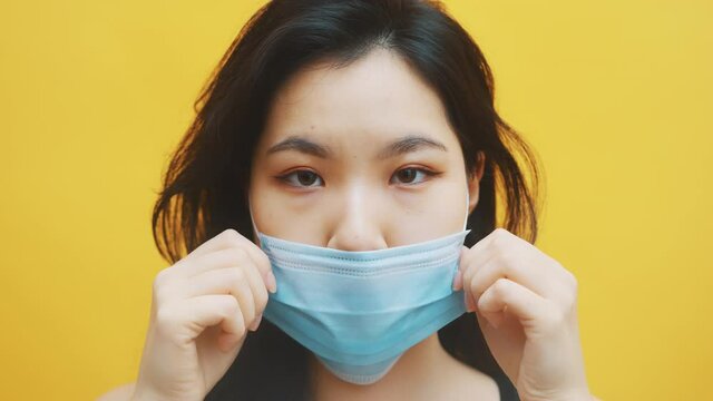 Young asian woman putting on medical mask. Close up. Prevention of the covid-19 spread. High quality 4k footage