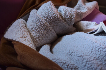 book on a cozy soft chair with chunky blanket candinavian style, hygge, cozy concept.