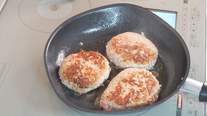 ハンバーグにフライパンで火を通す調理シーン