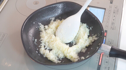 みじん切りにした玉ねぎをフライパンで炒めていく様子