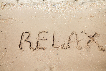 Handwritten Relax Word on the Sand Coast. Wonderful words on beach sand. Love idea concept.