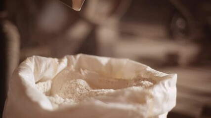 A baker prepares flour on his traditional wooden table, takes flour from the sack with scoop. Concept of/ tradition, flour, bakery