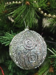 A silver ball weighs on a Christmas tree.