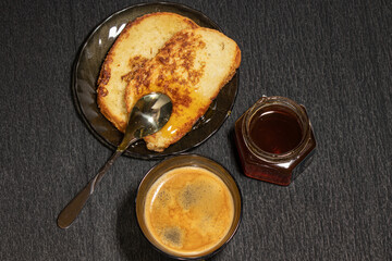 Cup of coffee with croutons and honey on a black background with nuts