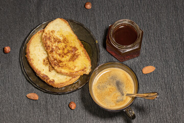 Cup of coffee with croutons and honey on a black background with nuts