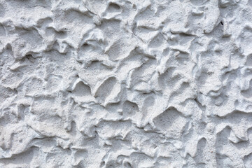 Fragment of a three-dimensional large-relief texture of textured plaster on the exterior of the Foundation of a house outdoor.