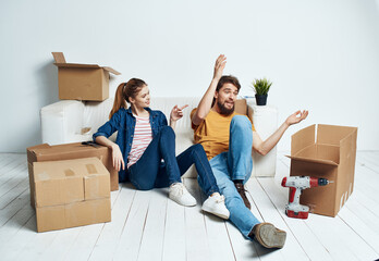 Fototapeta na wymiar Married couple man and woman on wooden floor with boxes moving flower in a pot repair work