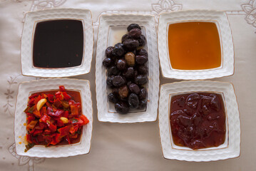 Jam, olive, honey, boiled grape juice and sauce on white porcelain plates on the table. Classical turkish breakfast.