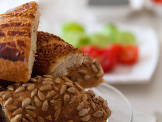 Piece of Turkish bagel and pastry on the plate white cucumber and tomato in the background and out of focus.