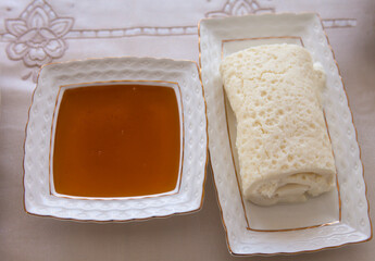 Honey and Cream or Butter next to each other on ceramic plates on a table.