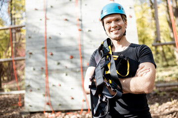 Portrait of a happy man well equipped with protective climbing equipment at amusement park outdoors
