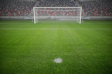 Shallow depth of field (selective focus) image with the penalty kick point on an empty soccer stadium.