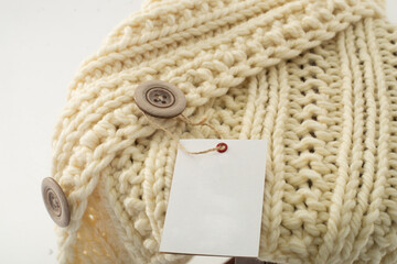 tag on a sweater with a large knit and a large button on a white background