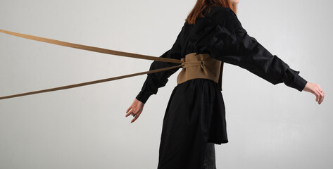 girl in black, held from behind with ropes on a white background, unrecognizable