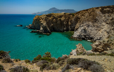 Fototapeta na wymiar Jagged cliffs plunge into the turquoise waters of the Mediterranean Sea at Tsigrado beach, Milos, Greece