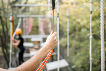 Well-equipped man having an active recreation, climbing in a rope park with obstacles in the forest, close-up on hand