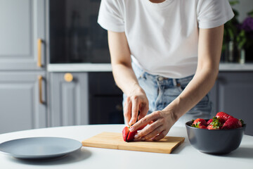 Close-up of the hands of a girl who cuts strawberry. Healthy food