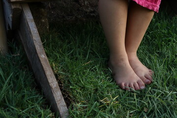 pies de niña sobre pasto y madera