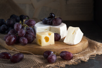 Composition of fresh grapes with cheese on a wooden background.