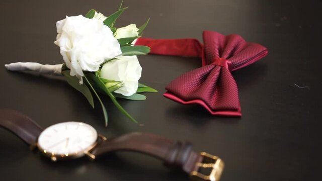 men's attributes, red bow tie, men's wrist watch and flowers in buttonhole boutonniere