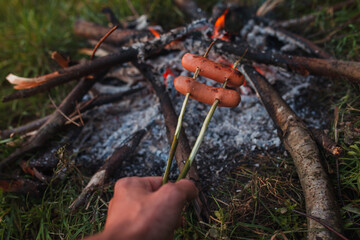 sausages are fried on a campfire