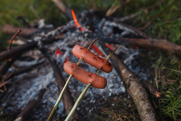 sausages are fried on a campfire
