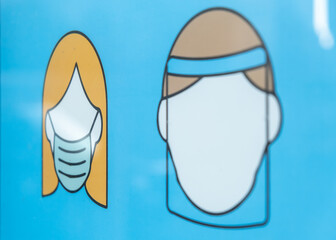 Graphics in a shop window showing people wearing a face mask to remind customers about the rule of wearing a face mask because of the COVID-19 pandemic