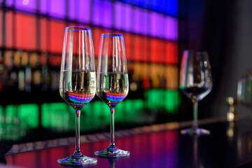 white wine glasses on bar counter in restaurant with colored panel on the background