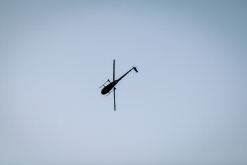 Silhouette of a chopper high in the blue sky seen from below, the military maneuvers; worm’s eye view.