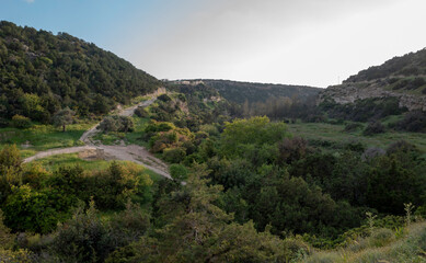 Fototapeta premium Sandy mountain road of the island of Cyprus in the light of the setting sun.