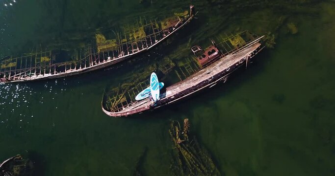Couple of sup surfers near shipwrecks on Barents Sea, aerial view. High quality 4k footage