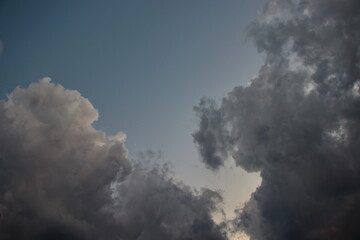 white cumulus clouds colored with shades of gray, framing a patch of heavenly gradient sky.