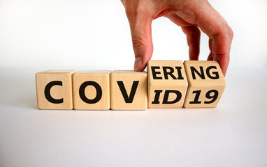 Covering covid-19. Male hand turns cubes with words 'covering covid19'. Covid-19 postpandemic concept. Beautiful white background, copy space.