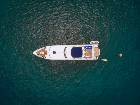 Drone shot of the beautiful white yacht in the warm blue sea; millionaire concept.