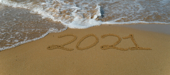 Happy new year 2021 written in the sand.Happy new year 2021 written in the sand by the sea.