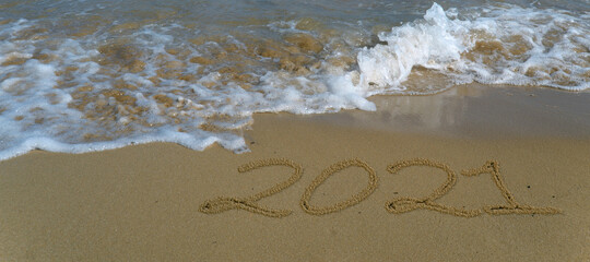 Happy new year 2021 written in the sand.Happy new year 2021 written in the sand by the sea.