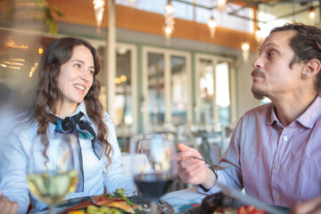 Close-up of a happy young mixed race couple having lunch in a rustic restaurant, celebrating birthday or anniversary
