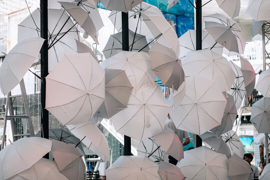 A lot of white open umbrellas are hanging on a pillar