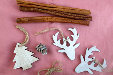 Various Christmas decorations and cinnamon sticks on pink background. Top view.