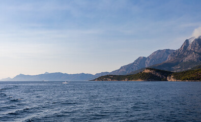 Fototapeta na wymiar Blick vom Meer auf die Küste in Kroatien. Berge mit Rauchwolken am Himmel. Panorama