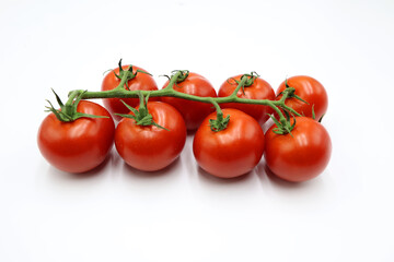 Red ripe fresh cherry cocktail tomatoes on the green stem isolated on white background