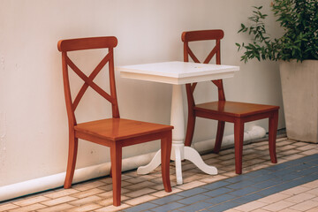 Two wooden brown chairs are next to a snow-white table in a light-colored house