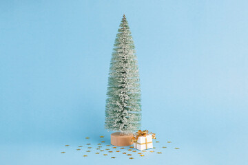 Christmas snowy tree and gift on pastel blue background. Minimal New year concept. Magic pine tree